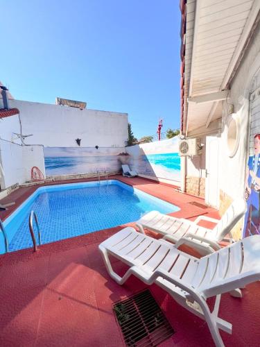 a swimming pool with two lounge chairs next to it at ApartHotel Maison Suisse in Asuncion