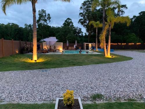 a garden with palm trees and a swimming pool at Casa para 4 personas en vista24uy, Bella Vista, Maldonado in Balneario Solís