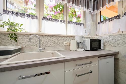 een keuken met een spoelbak en twee ramen bij Apartmani Oaza in Trogir