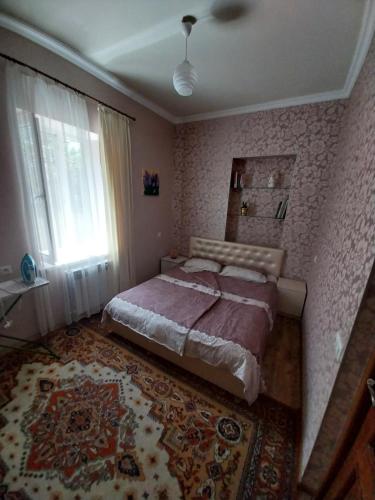 a bedroom with a bed and a window and a rug at Like Home Guesthouse in Yerevan