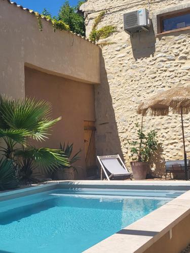 - une piscine en face d'un bâtiment avec une maison dans l'établissement So Home, à Saint-Pantaléon-les-Vignes