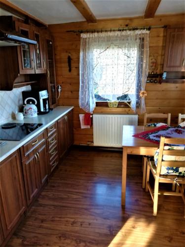 a kitchen with wooden cabinets and a table and a window at Adelka-dom przy stoku in Krynica Zdrój