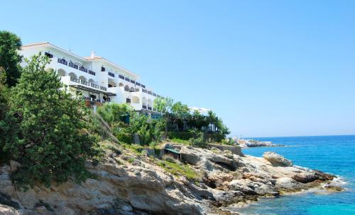 a building on a cliff next to the ocean at Erofili Beach Hotel in Armenistis