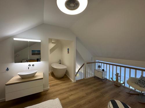 a bathroom with a sink and a tub in a attic at MEERzeit unter Reet in Braderup