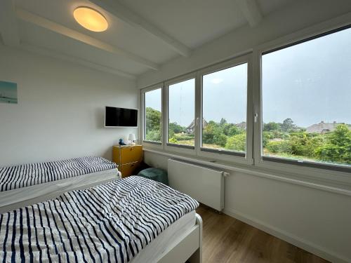 a bedroom with two beds and windows with a view at MEERzeit unter Reet in Braderup