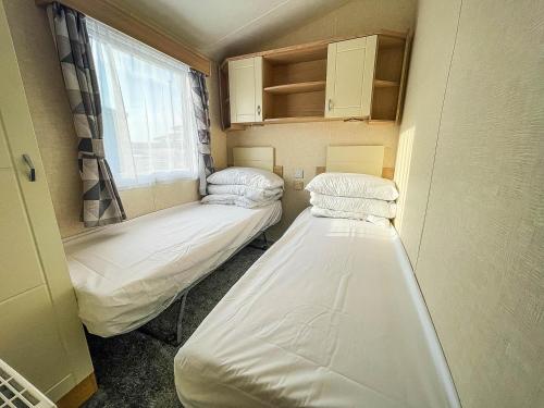 two beds in a small room with a window at Lovely 8 Berth Caravan Nearby Scratby Beach In Norfolk Ref 50021f in Great Yarmouth