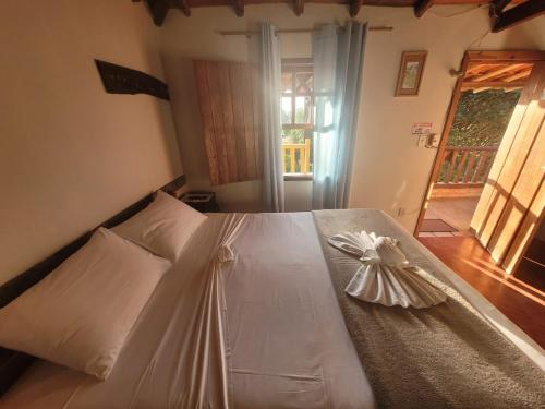 a bedroom with a white bed with a bow on it at Pousada Luar do Rosário in Milho Verde