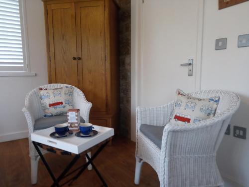 two chairs and a coffee table in a living room at Lamorna Pottery B&B in Penzance