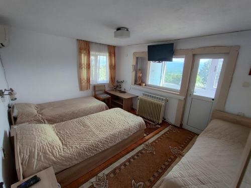 1 dormitorio con 2 camas, escritorio y ventana en Къща за гости Слънце Борики, en Gabrovo