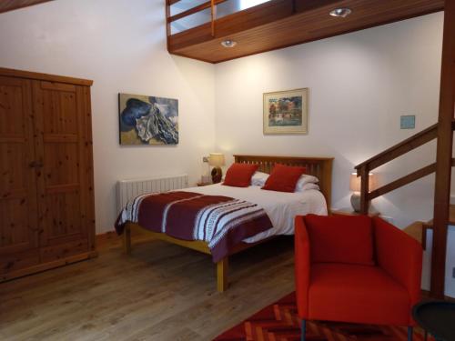 a bedroom with a bed and a red chair at Lamorna Pottery B&B in Penzance