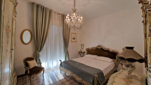 a bedroom with a bed and a chandelier and a chair at Villa Sicels - Agnone Beach - Syracuse in Agnone Bagni