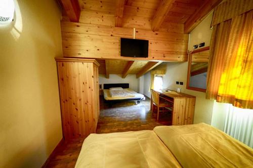 a room with a bedroom with a bed and a desk at Garni Baita Cecilia in Livigno