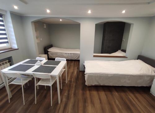 a room with two beds and a table and chairs at Agroturystyka Huta in Krzywe