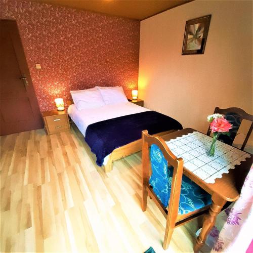 a bedroom with a bed and a table with a vase at Willa Kamieniec in Polańczyk