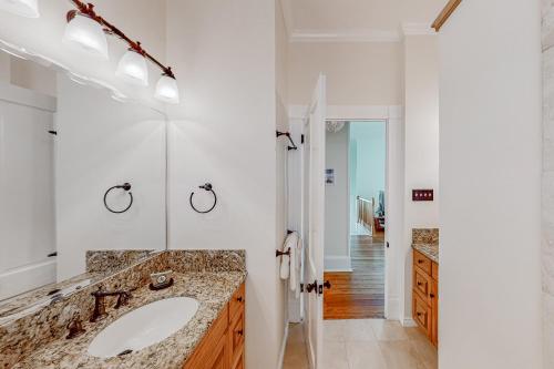 La salle de bains blanche est pourvue d'un lavabo et d'un miroir. dans l'établissement Coastal Breeze, à Galveston