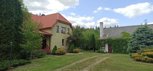 的住宿－Rychtyńska Cisza，一座黄色的房子,有红色的屋顶和院子
