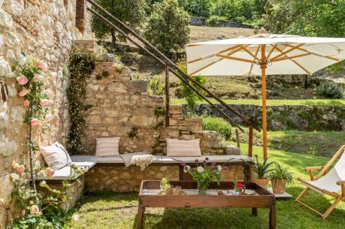 a garden with a bench and an umbrella and a table at Borgo di Pianciano in Spoleto