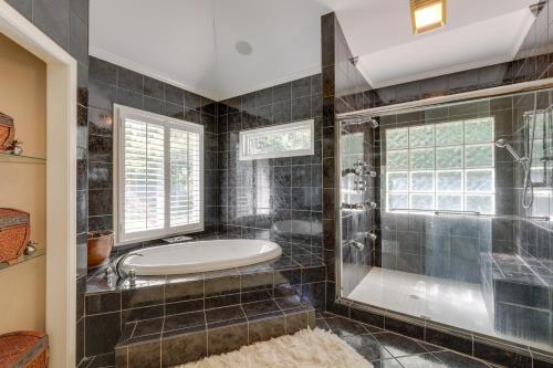 La salle de bains est pourvue d'une baignoire et d'une douche en verre. dans l'établissement Chic Georgia Abode with Home Theater, Pool and Hot Tub, à Ellenwood
