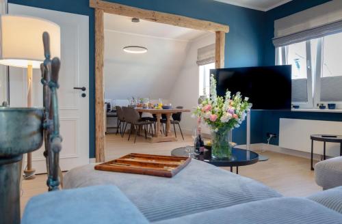 a living room with blue walls and a table with flowers at Backbord in Westerland (Sylt)