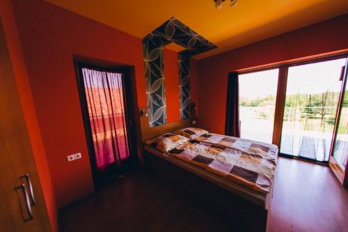 a bedroom with orange walls and a bed with a window at Aqua Villa in Siófok