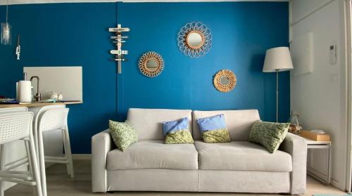 sala de estar con sofá y pared azul en Charmant T2 avec grande terrasse et confort 3 étoiles, en La Grande-Motte