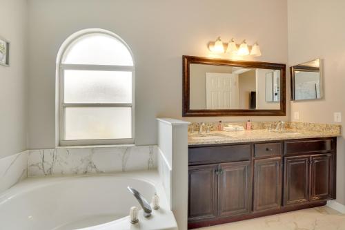 a bathroom with a tub and a sink and a mirror at Minneola Home with Screened Porch, 25 Mi to Disney! in Minneola