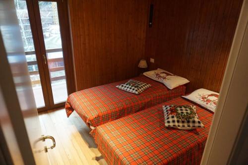 two twin beds in a room with a window at Miri Apartment in Alagna Valsesia