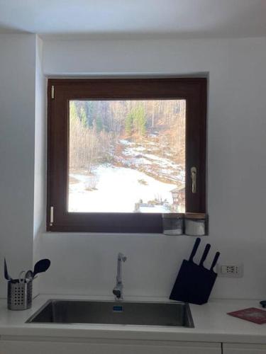 a kitchen sink with a window with a view of a snow field at Miri Apartment in Alagna Valsesia