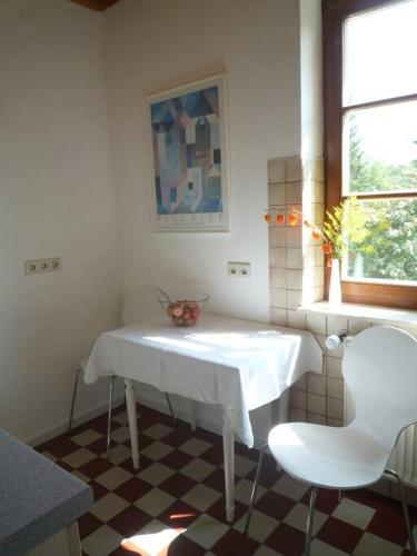 een witte keuken met een tafel en 2 stoelen bij Ferienwohnung am Donauradwanderweg in Riedlingen
