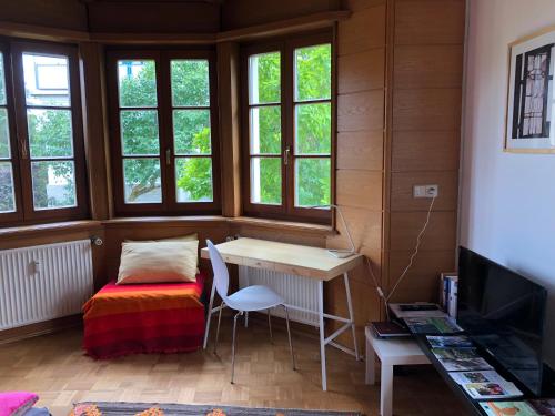 een kamer met een bureau, een tafel en ramen bij Ferienwohnung am Donauradwanderweg in Riedlingen