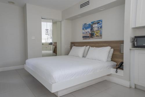 a white bedroom with a large bed and a television at The Biscayne Hotel in Miami