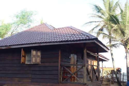 a small wooden house with windows and a palm tree at Robinson's Hut in Bure Town
