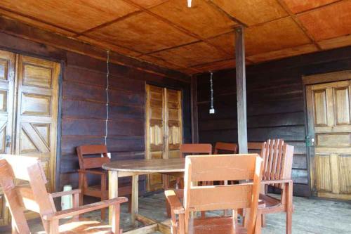 Robinson's Hut في Bure Town: غرفة طعام مع طاولة وكراسي خشبية