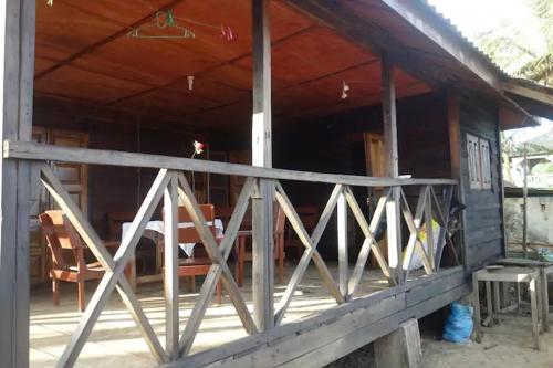 een veranda van een houten huis met een houten hek bij Robinson's Hut in Bure Town