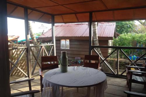 een patio met een tafel en stoelen op een veranda bij Robinson's Hut in Bure Town