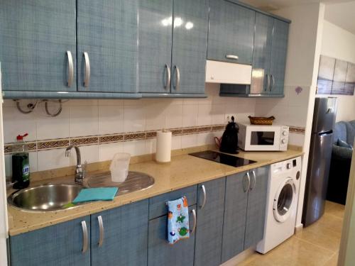 uma cozinha com armários azuis, um lavatório e um micro-ondas em Apto Puipana em Corralejo