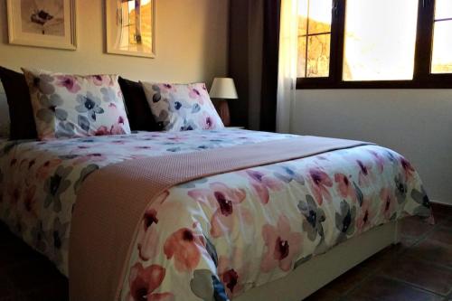 um quarto com uma cama com colcha floral e uma janela em Casa Guiguan em Tinguatón