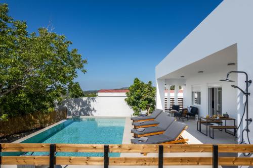 a villa with a swimming pool and lounge chairs at Aelia Luxury Villa in Sálakos