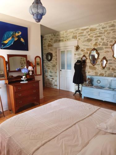une chambre avec un lit et un mur en pierre dans l'établissement La ferme de Lec'h Hameury, à Plestin-les-Grèves