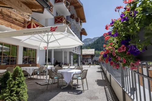 un restaurante con mesas, sillas y flores al lado de un edificio en Hotel Sportalmmm, Hoch-Genuss en Zauchensee