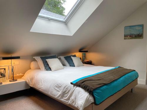 a bedroom with a large white bed with a skylight at L'Art de la fugue in Daverdisse