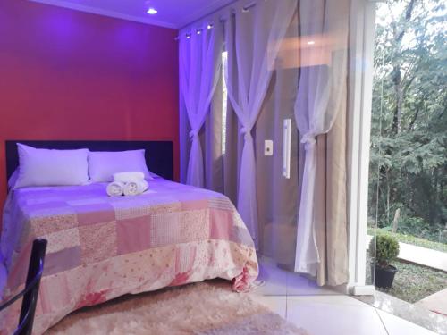 a purple bedroom with a bed and a window at Parada Di Maria Guest House in Campos do Jordão