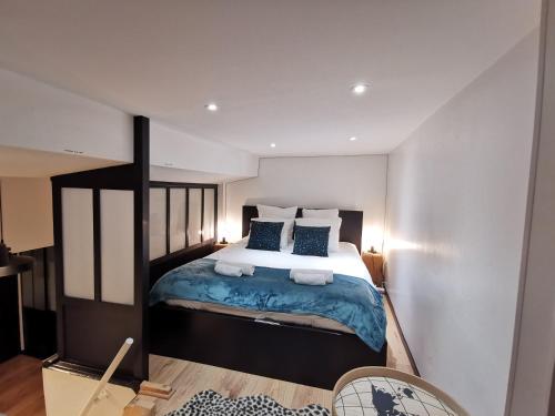 een slaapkamer met een groot bed met blauwe lakens en kussens bij Nouveau - Au coin du Château in Nantes