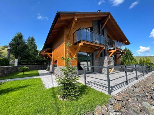 a wooden house with a balcony and a lawn at Chalet Filipsky Deluxe in Ždiar