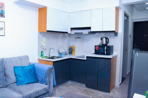 a kitchen with a couch and a kitchen with white cabinets at Heartland Gardens Apartments Kilimani Nairobi in Nairobi