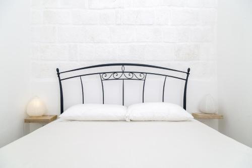 een wit bed met een zwart hoofdeinde in een slaapkamer bij Borgo Albergo Capozzi 41 in Monopoli