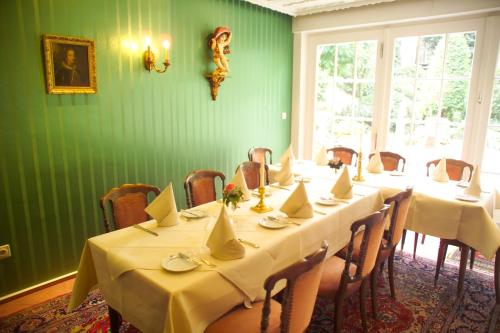 a dining room with tables and chairs and a green wall at Hotel Zum Alten Brunnen in Rheine