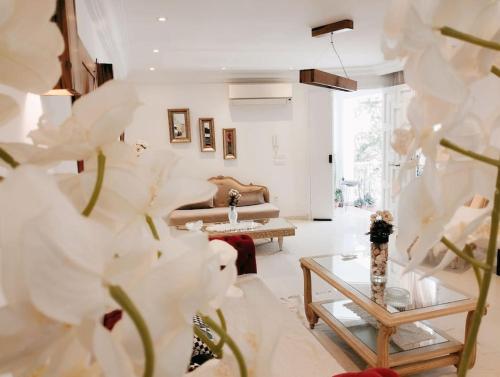 a living room with white furniture and white flowers at Spacieuse et Cosy in El Haouach