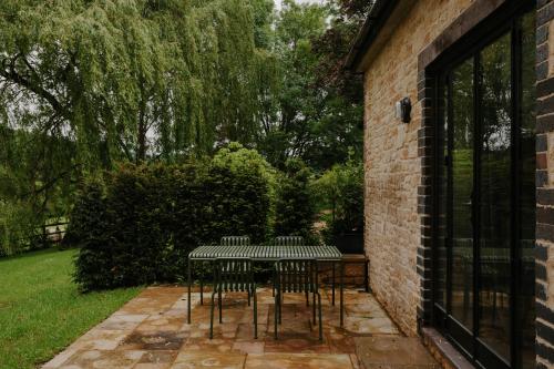 a table with four chairs next to a brick wall at The Cotswold Farm Hideaway in Alderley