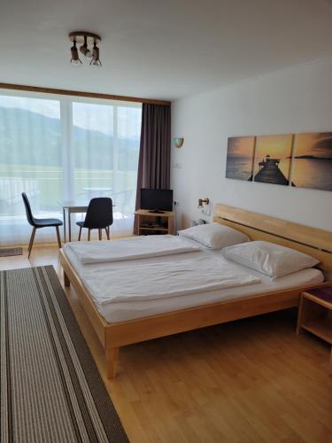 a bedroom with a large bed and a table with a chair at Gästezimmer Suppan in Hörbranz